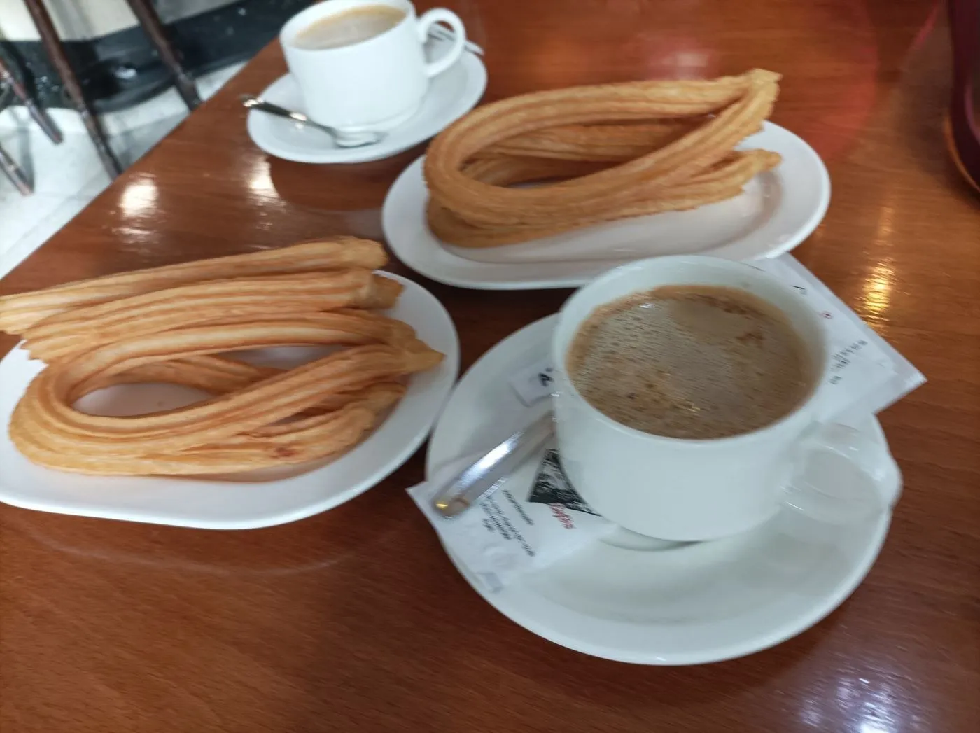 Dos platos de churros y dos tazas de café sobre una mesa de madera