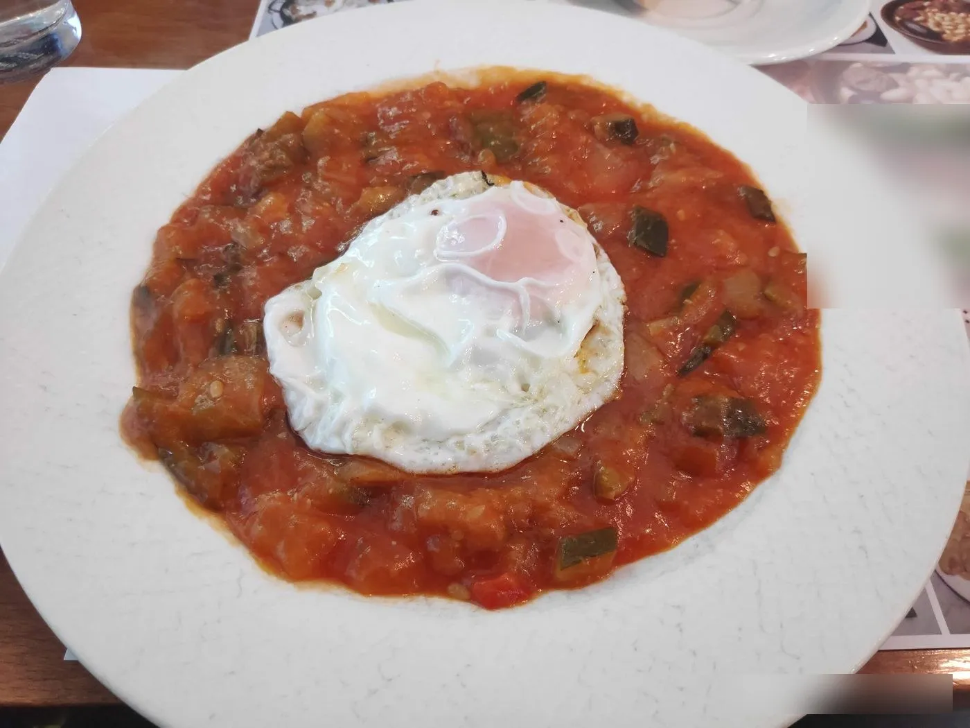 Plato hondo de pisto con un huevo frito encima
